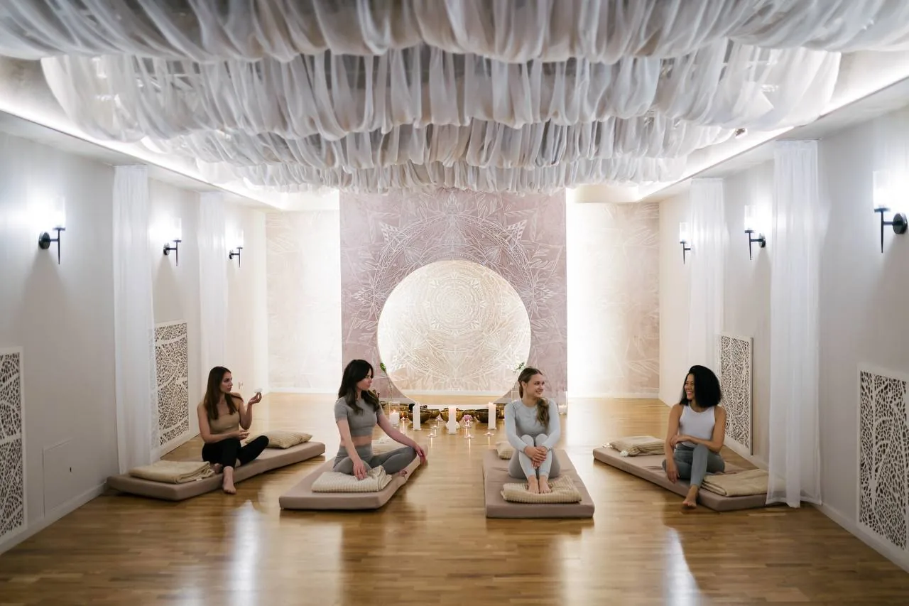 Женщины сидят на подушках в светлой комнате для медитации и утренних практик