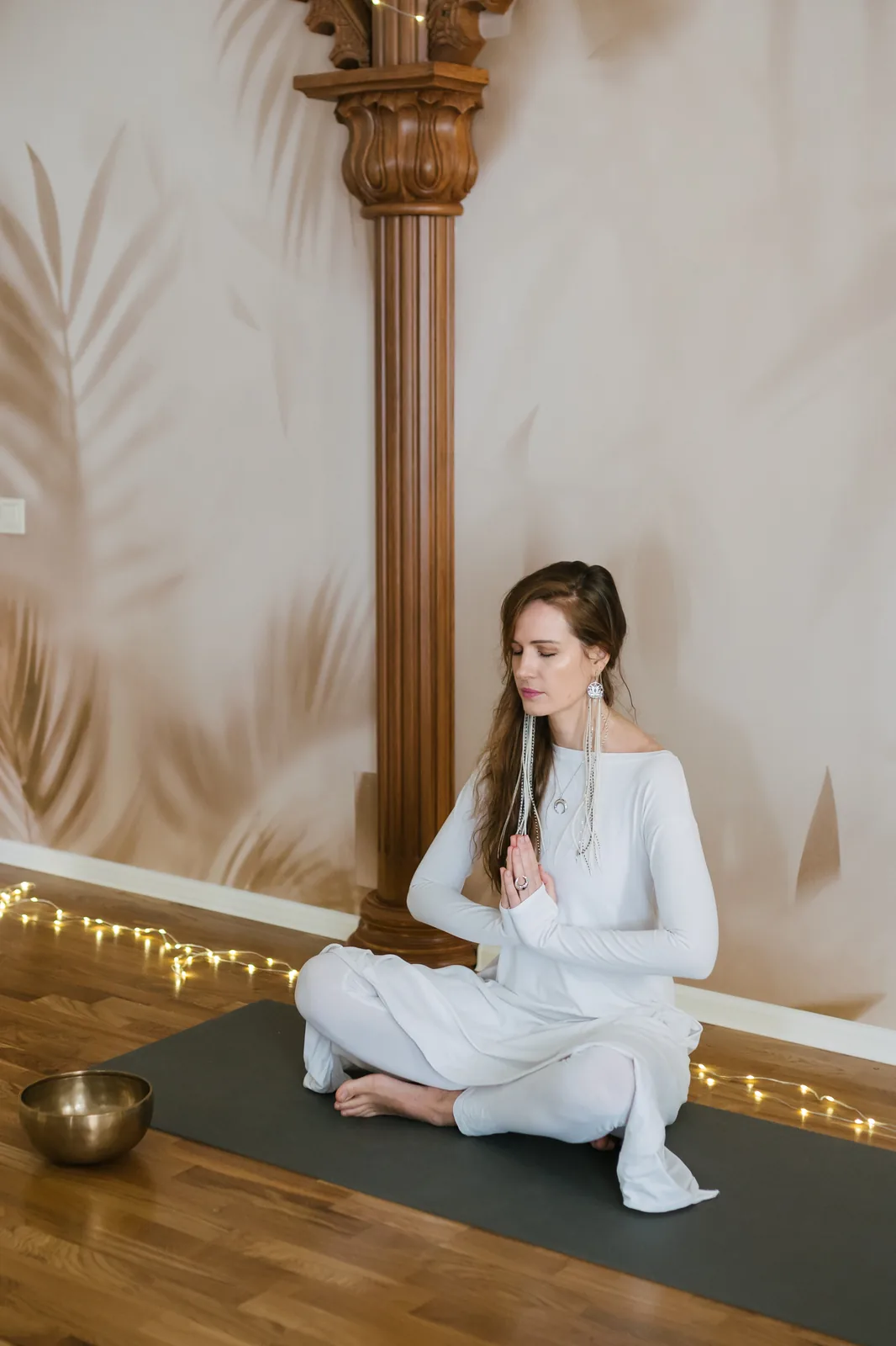 Женщина медитирует на коврике рядом с колонной в спокойной обстановке для йоги